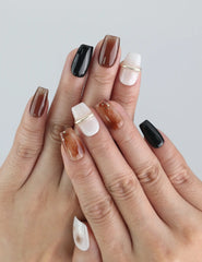 Hand wearing Naillover Blend Black press on nails, showing off multi-tone design with pearls and gold detailing.