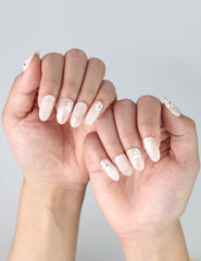 Fingers posed to showcase Naillover’s handmade press on nails with pink and white flowers over a sheer base