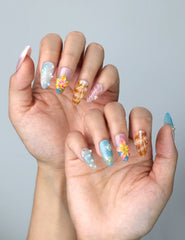 Side view of beachy almond nails with pastel pink blossoms, pearlescent texture, and sea-themed accents