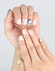 Close-up of fingers posed to show 3D white flower nails with a delicate French gradient over olive tones by Naillover