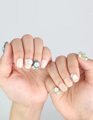 Hands spread to display Naillover’s handmade floral press on nails with olive and nude French fade blend