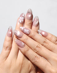 Hand wearing Blush Blossom Sparkle Singapore press on nails with pink base, white floral designs, and metallic accents, handmade by naillover.