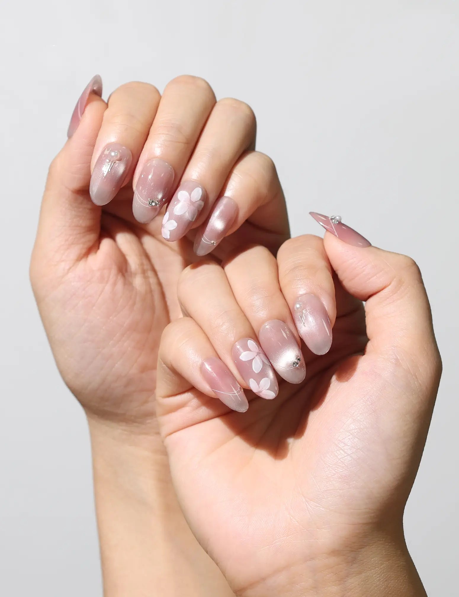 Close-up of Blush Blossom Sparkle Singapore press on nails on hand, highlighting intricate handmade floral patterns.