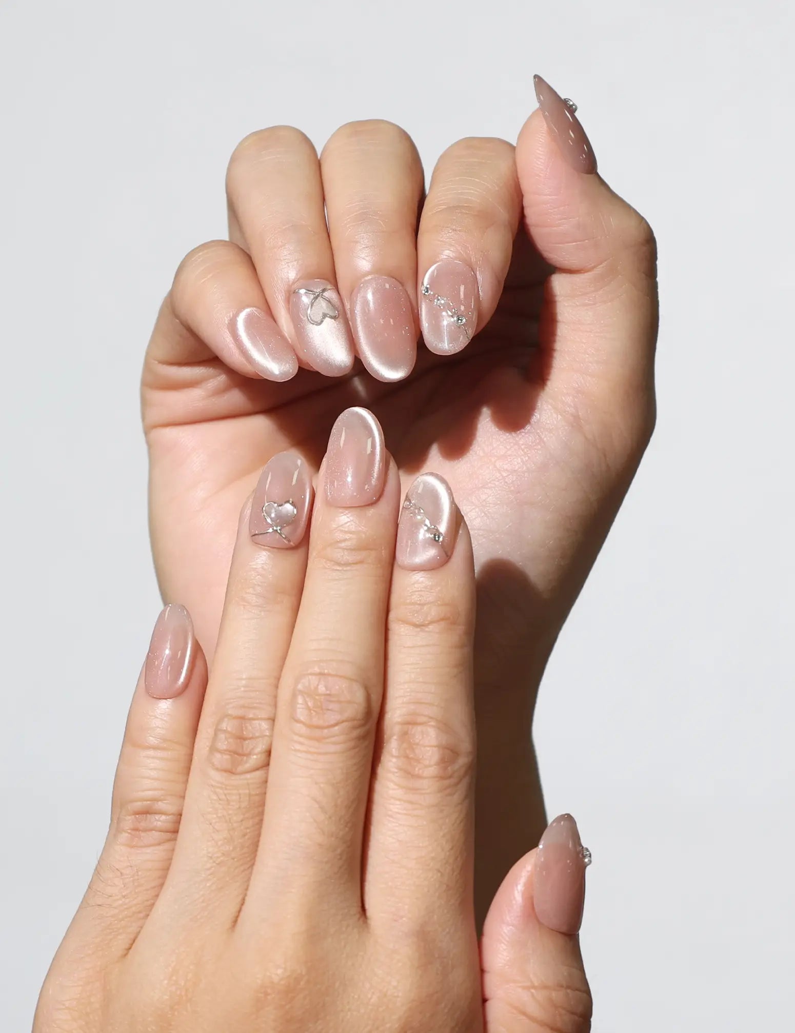 Hand close-up showing Blush Gleam Cat Eye handmade Singapore press on nails with elegant silver sparkle – naillover.