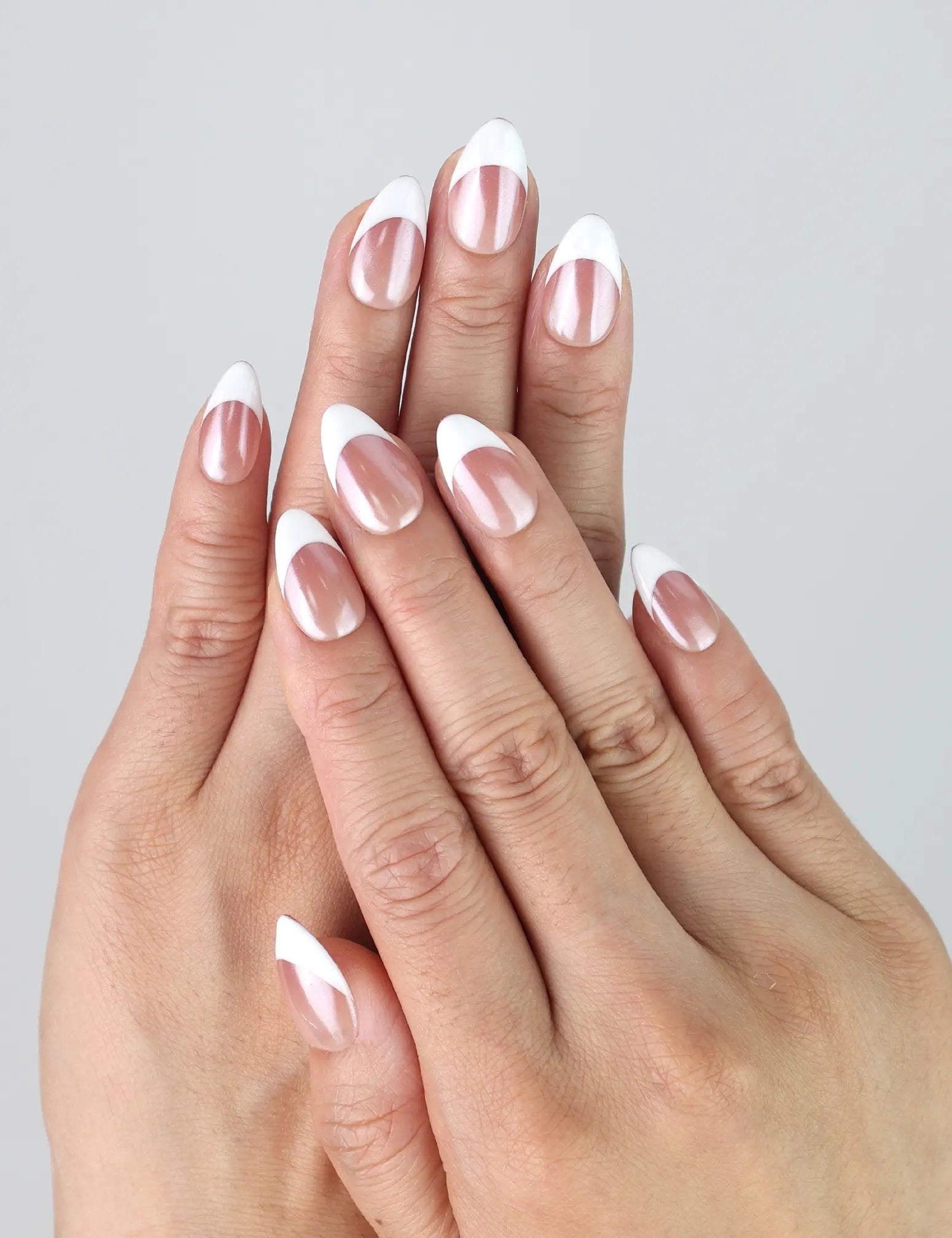 Hand model wearing short almond press-on nails with a smooth taupe-to-white gradient finish