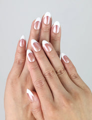 Hand model wearing short almond press-on nails with a smooth taupe-to-white gradient finish
