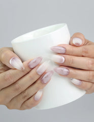Hand holding a cup, showcasing Naillover’s ombré pink nails with butterfly embellishments in an airy, feminine style