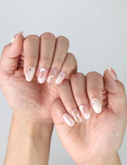 Side view of short oval pink nails with floral nail art and glimmering pearl embellishments