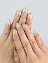 Model hand wearing Naillover Clean Sand press on nails in almond shape, showing soft gradient and geometric shimmer.