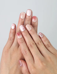 Hand posing with short squoval press on nails in soft nude shades, featuring delicate pink flower nail art by Naillover