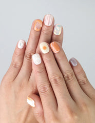 Hand gesture showcasing coral-inspired press on nails in tropical peach and seafoam green tones by Naillover