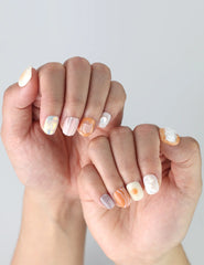 Close-up of hands wearing tropical-themed coral press on nails in pastel peach and soft green hues by Naillover