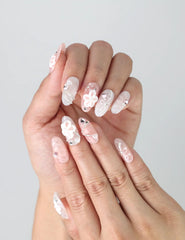 Close-up of Naillover’s handmade press-on nails in soft pink featuring sculpted blooms, glittering gems, and heart accents