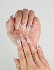 Hand wearing Floral Flicker handmade press on nails, elegant floral design with sparkling accents for trendy and elegant looks.