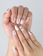 Fingers posed with Naillover handmade nails featuring subtle pink-white shimmer and delicate 3D flowers over gradient tones