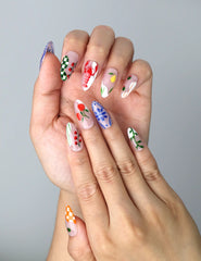 Close-up of Naillover’s handmade nails featuring whimsical cherry prints, soft daisy blooms, and colorful flower patterns