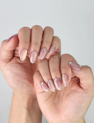 Side view of handmade pink gradient nails with chrome shine and tiny gem accents in short oval shape