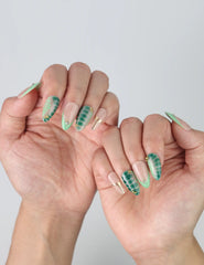 Side view of Naillover short almond press-on nails with fresh green foliage art and elegant metallic gold detailing