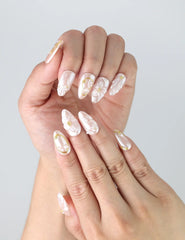 Close-up of short press on nails with soft pink base, dimensional white flowers, and metallic gold accents by Naillover