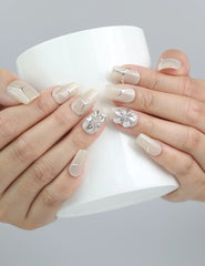 Hand holding a cup, showcasing Naillover’s ivory nails with elegant flower detailing in a modern square shape