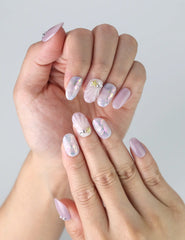 Fingers displayed wearing Singapore handmade nails with a dreamy lavender gradient and shimmery holographic details