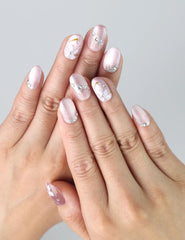 Hand gesture displaying pink handmade press on nails with delicate floral design and rhinestone accents by Naillover