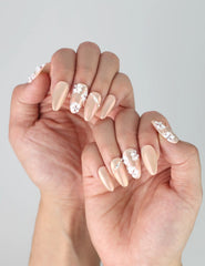 Side view of almond-shaped press-on nails with luminous pink polish and sculpted white flowers
