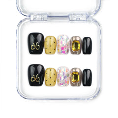 Non-worn view of Luxe Mix handmade Singapore press on nails in black, gold, and glitter with gem accents, naillover