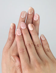 Close-up of hand wearing Naillover handmade pink and white marbled press on nails showing smooth glossy finish.