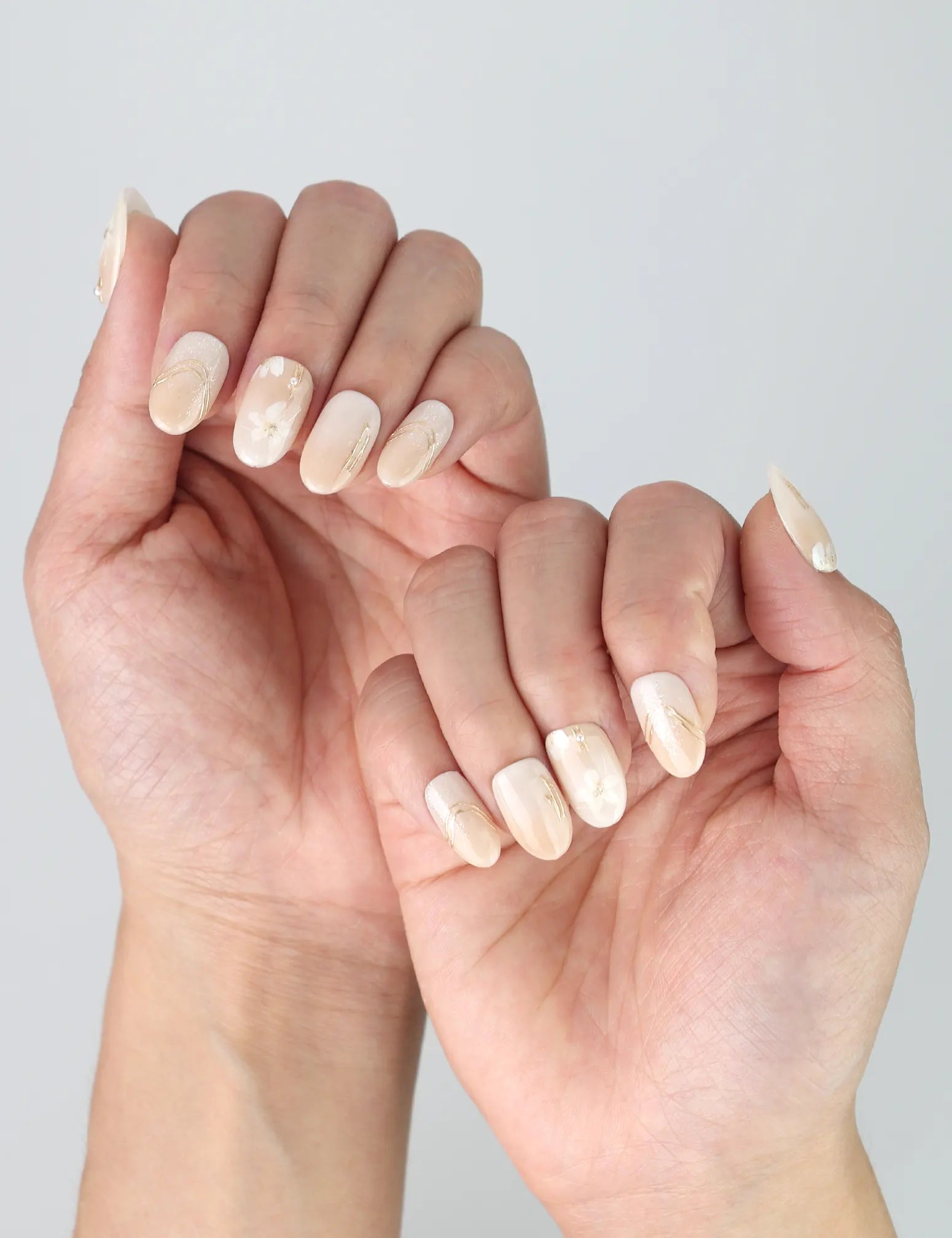 Side view of minimalist short oval nails with glossy greige polish and subtle gold sparkle