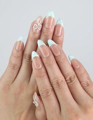 Close-up of Naillover Mint Chic press on nails on hand, showing mint green tips and tiny pearl bows in natural light.