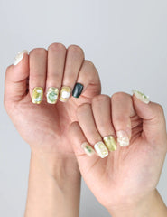 Side view of short square nails in pastel mint and white with raised flower embellishments and gold touches