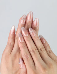 Hand model wearing medium oval press-on nails with soft shimmer gradient and delicate silver flower accents