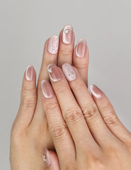 Hand wearing Naillover Misty Rose handmade press on nails with shimmering cat eye nails effect and silver accents.