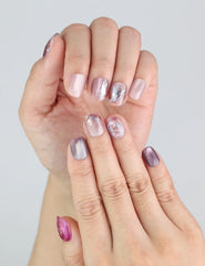Model hand shows Amethyst Shimmer short press on nails with 3D rose and lavender tones.