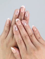 Model wearing Naillover Blush Bowlet nails—short oval nude press on nails with heart and bow accents.