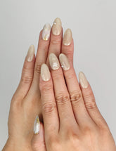 Model wearing Naillover Cappuccino Daisy handmade press on nails Singapore with beige base and floral design.