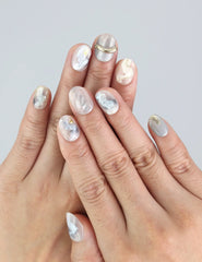 Naillover Clear Gleam press on nails worn on hand, showcasing soft marble textures and gold foil details.