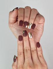 Close-up of Naillover Crimson Glint handmade nails showing glossy burgundy and metallic details