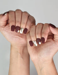 Fashion hand model wearing Naillover Crimson Glint burgundy press on nails with metallic accents