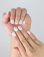 Close-up of Gentle Echo press on nails on fingers, showing simple floral design with a classic finish.