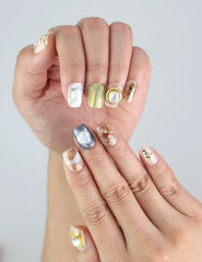 Hand model with Naillover handmade press on nails featuring gold leaf, opalescent gems, and floral touches from the Singapore collection.