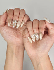 Close-up of Naillover Golden Brown Floral Shine handmade press on nails worn on hand with gold shimmer and leaf motifs.