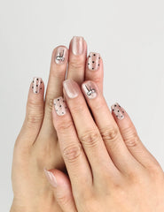 Hand wearing Naillover Mocha Dot Singapore press on nails with taupe base, polka dots, and bows in natural light