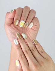 Side view of fingers featuring Nature's Glow handmade press on nails, showing fine floral lines and shimmering gold foil accents.