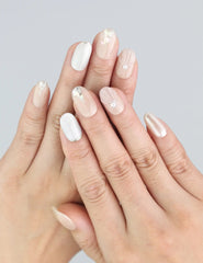Model wears Nude Gleam short oval press on nails with beige and silver sparkle by Naillover.