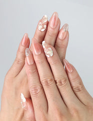 Hand wearing Peachy Glow pink floral press on nails, fingers slightly spread to show soft floral details