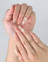 Close-up of fingers wearing Peachy Glow Singapore nails with pink flower accents and glossy finish