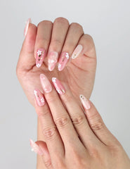 Close-up of Sakura handmade press on nails worn on fingers, highlighting lifelike floral accents and delicate spring tones.