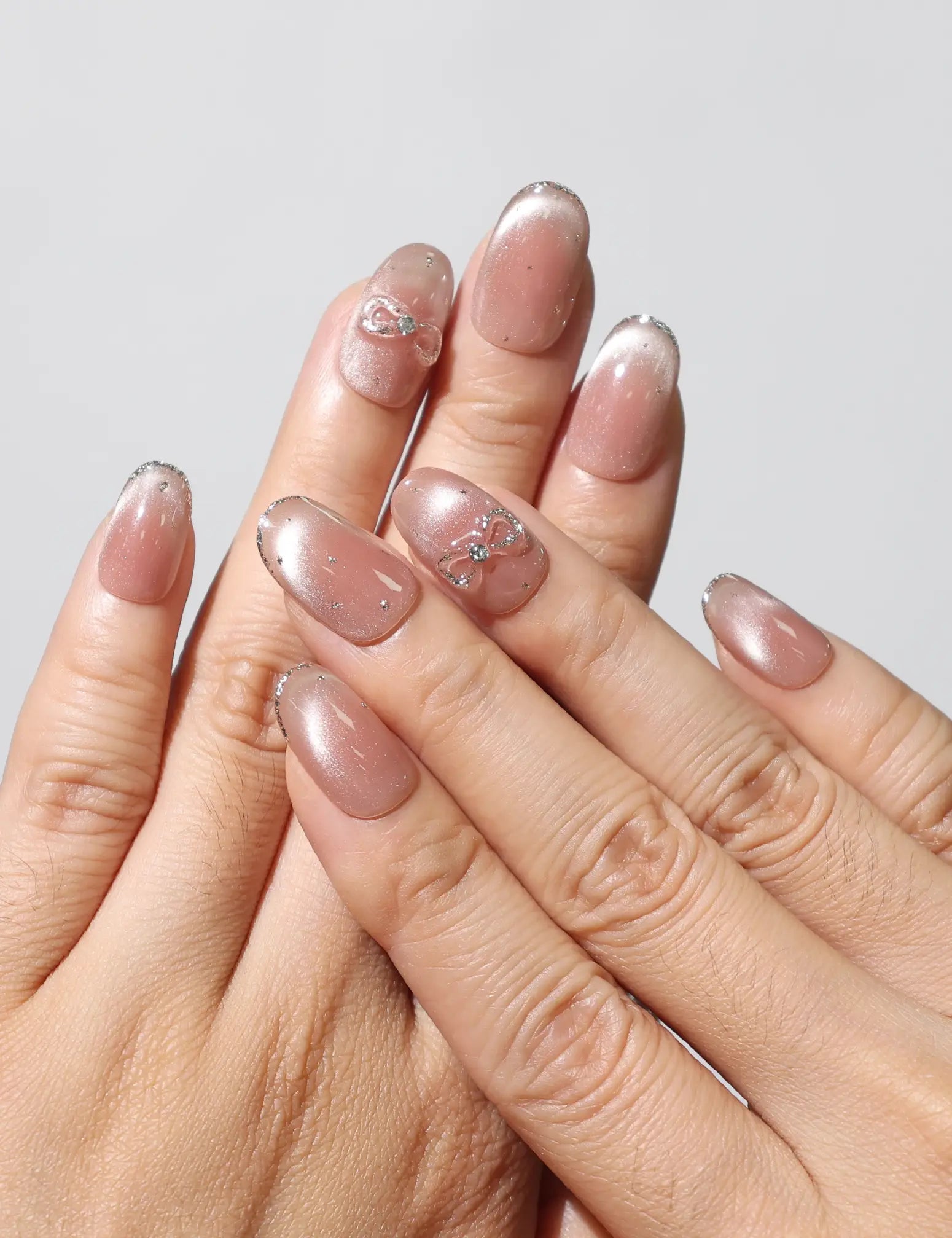 Wearing Sparkle Allure handmade gradient cat eye Singapore press on nails with silver bow accents by Naillover.